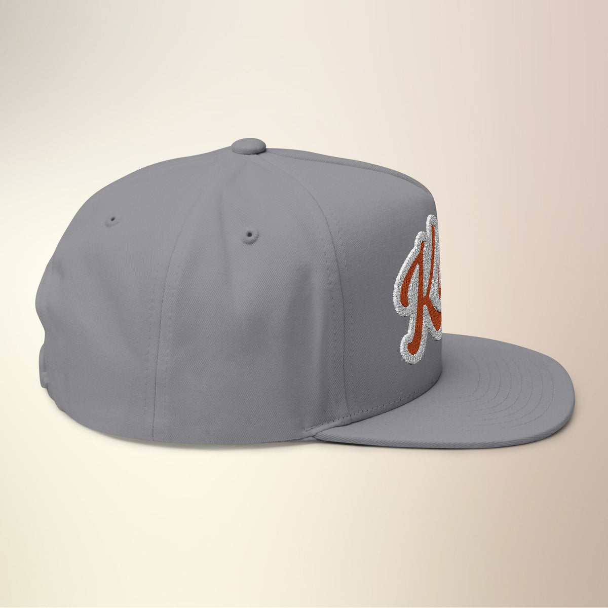 Side view of gray Kahu snapback cap with flat brim and embroidered logo