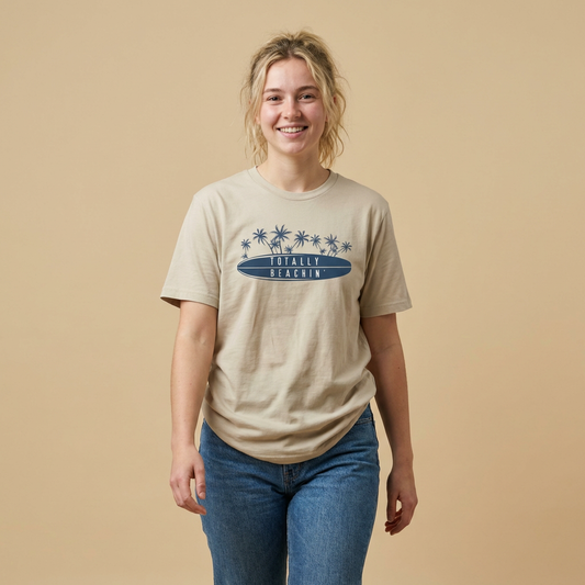 Person wearing a beige t-shirt  with 'TOTALLY BEACHIN' text and palm trees graphic design - Island Drops t-shirt collection | Unisex t-shirts