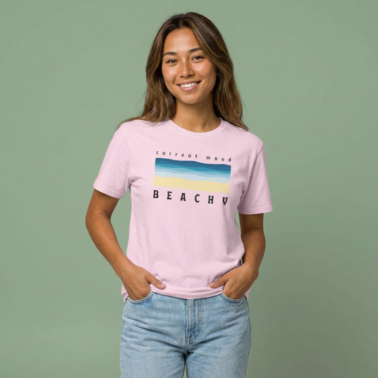 Person wearing a pink t-shirt with 'Current Mood Beachy' design with a stylized beach and ocean graphic design - Island Drops t-shirt collection | Unisex t-shirts