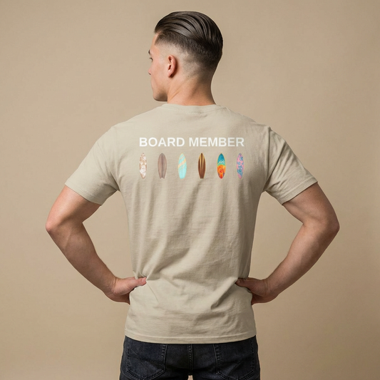 Man wearing a beige t-shirt with 'BOARD MEMBER' text and colorful surfboard icons on the back - Island Drops t-shirt collection | Unisex t-shirts