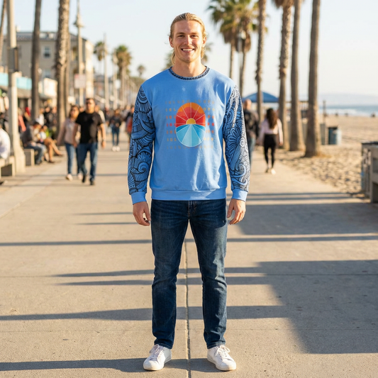 Person wearing a blue sweatshirt with 'ISLAND DROPS' text behind a graphic sunset and tribal tattoo sleeve pattern - Island Drops long sleeve collection | Unisex sweatshirt