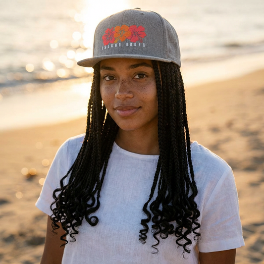 Person wearing a hat with 'ISLAND DROPS' text and hibiscus graphic design - Island Drops hat collection | Unisex snapback cap